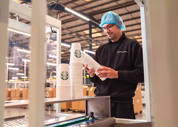 Man inspecting a stack of Starbucks cups before they leave packacing factory
